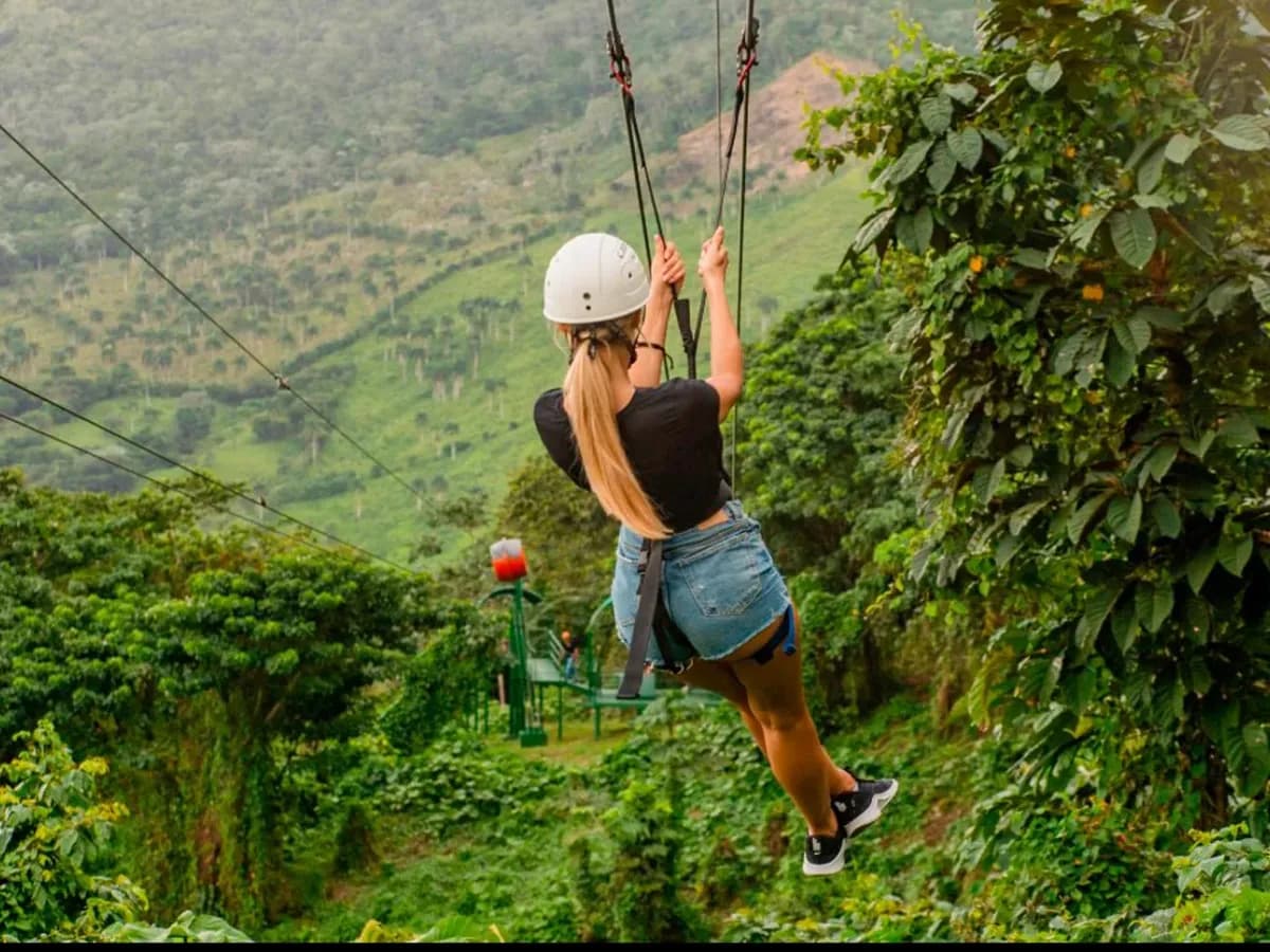 A zipline rider crossing high above a green valley