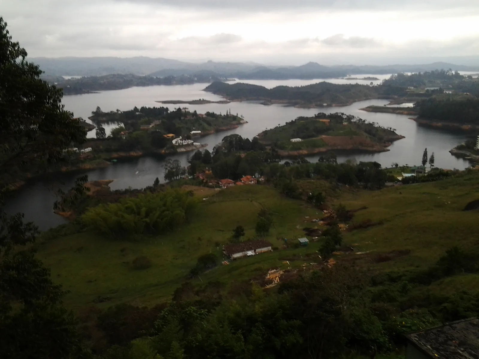 Green islands scattered across the Guatapé reservoir under a cloudy sky
