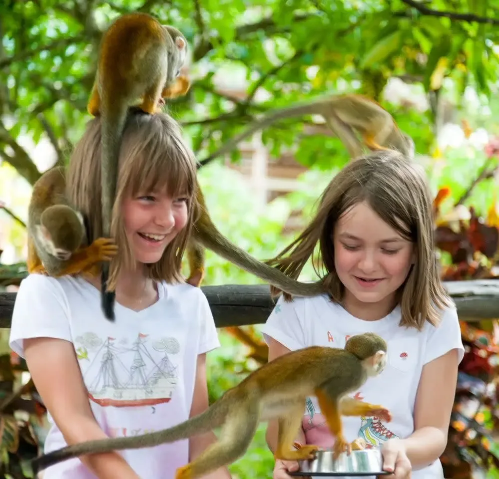 Two young visitors with squirrel monkeys on their shoulders
