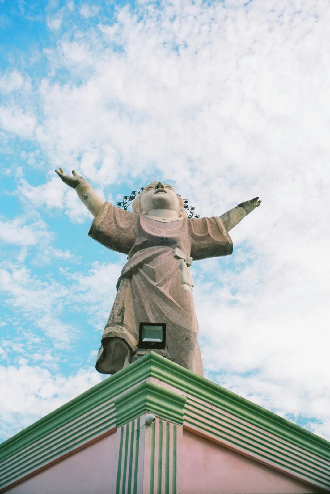A sculpted figure above a green historic building