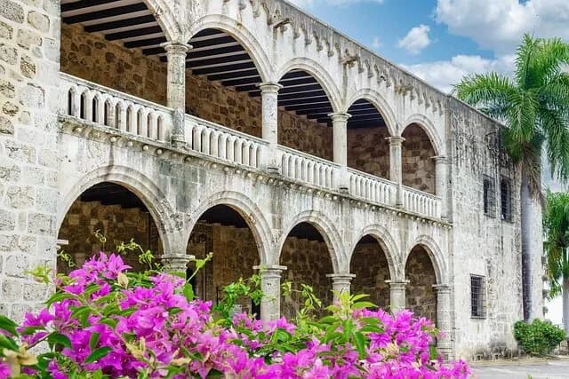A colonial stone palace with two tiers of arches and flowering bougainvillea