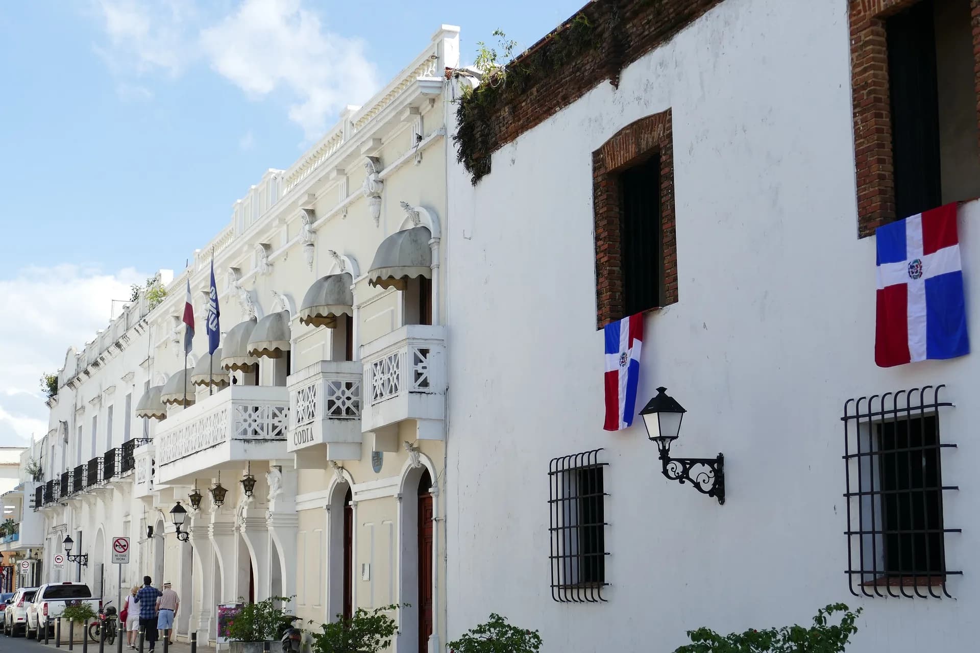Dominican flags hung along a white colonial facade with wrought-iron balconies