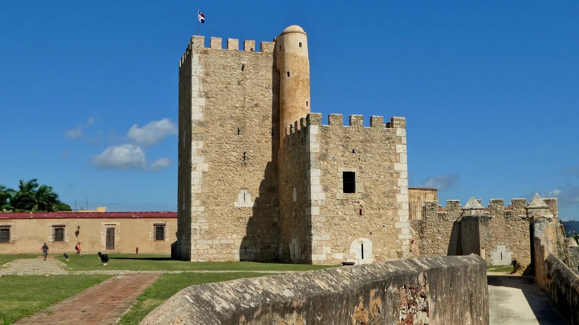 The stone tower and ramparts of a colonial fortress under a blue sky