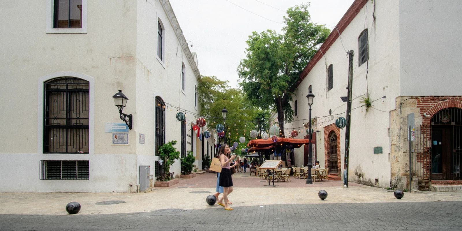 People exploring a street between historic stone buildings