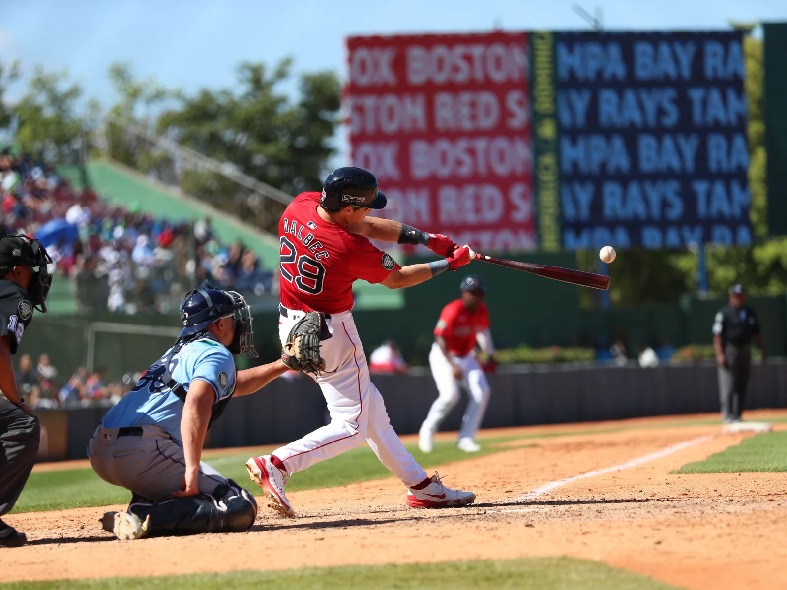 A batter connecting with a pitch at a packed baseball stadium