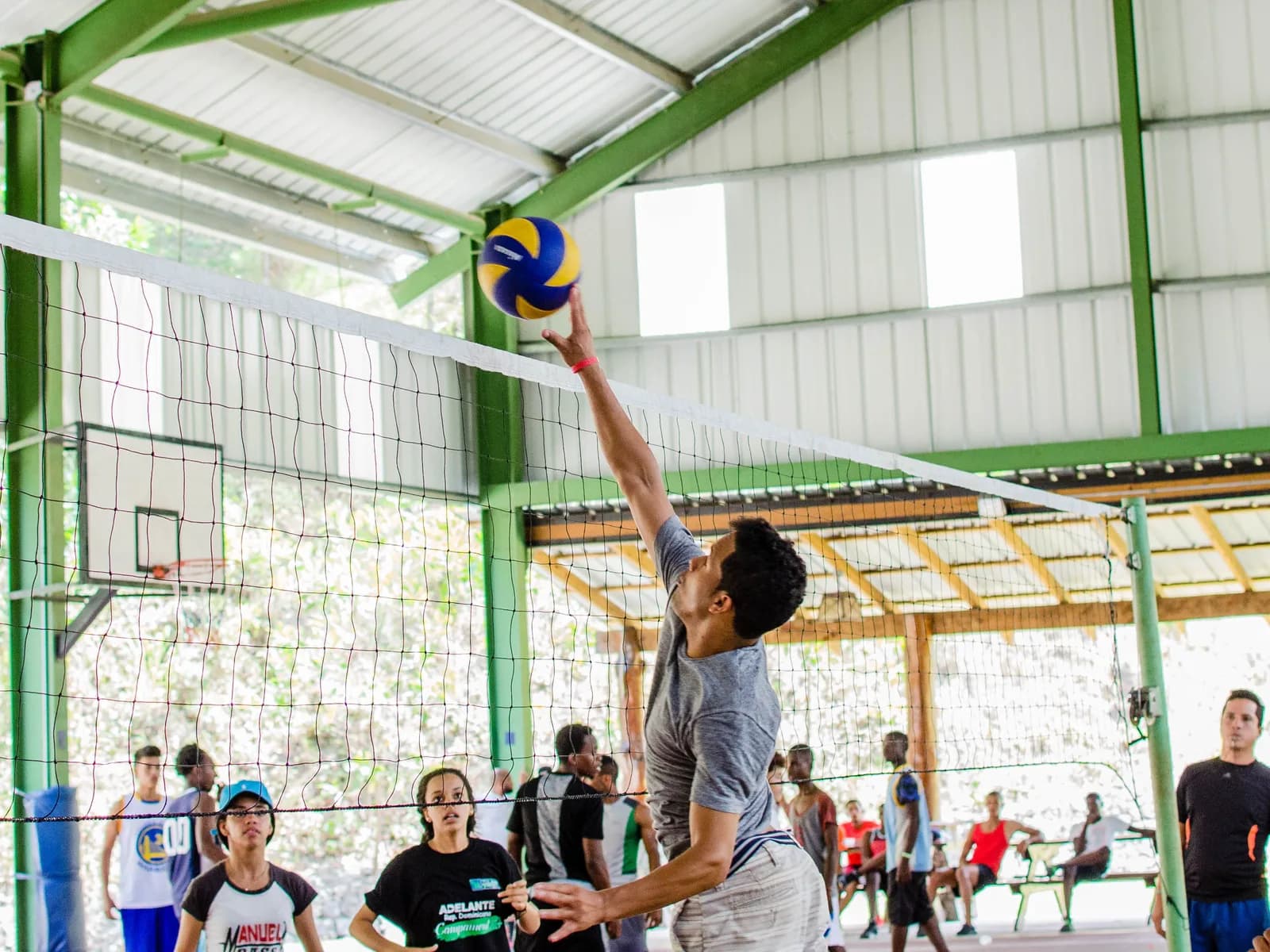 A player rising to attack at the net in an open-air Dominican volleyball gym