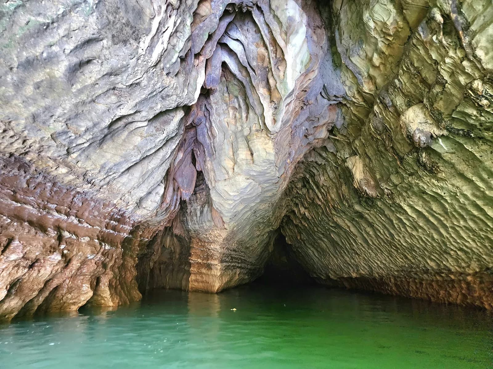 The mouth of a limestone cave with a river running through it