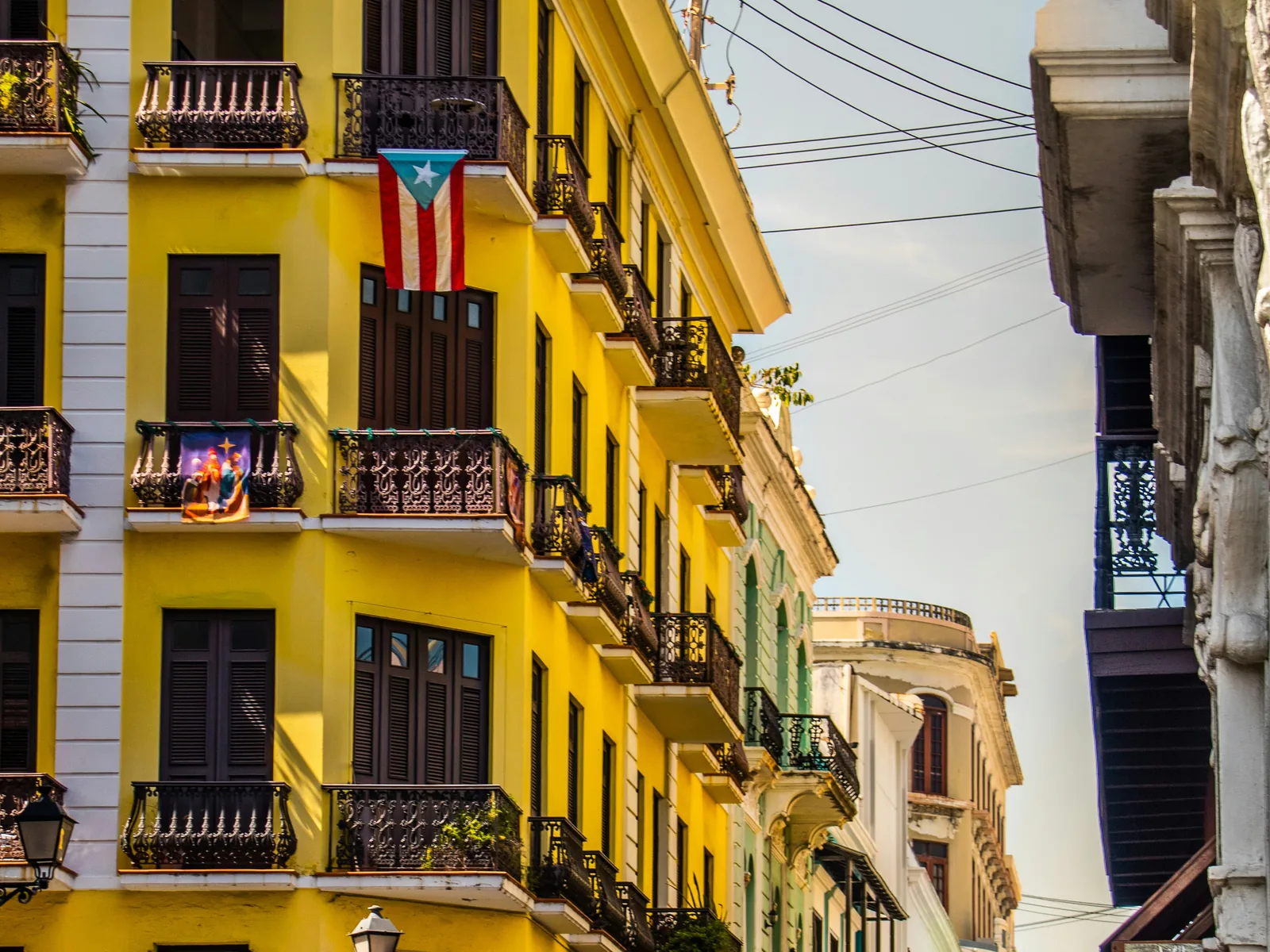 A Puerto Rican flag hanging from the balcony of a yellow building in Old San Juan