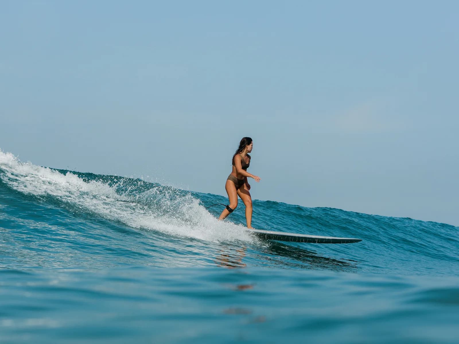 A surfer riding a small wave in clear blue water