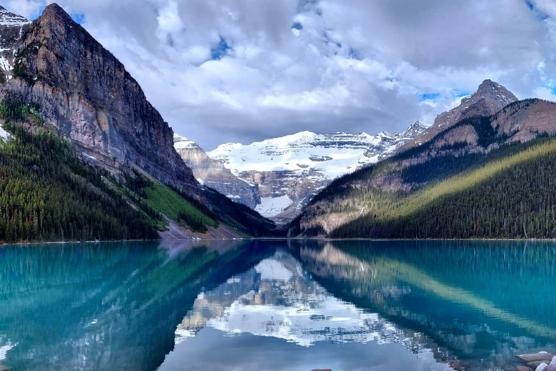 Snow-capped mountain peaks reflected in a turquoise alpine lake
