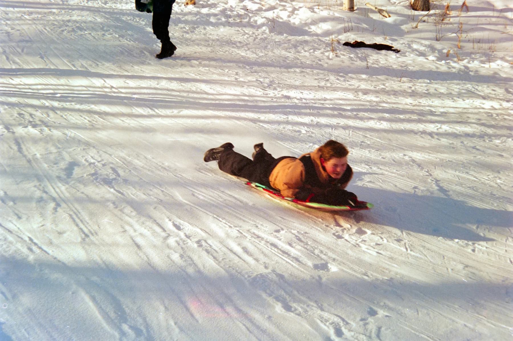 A sledder glides down a snowy hill