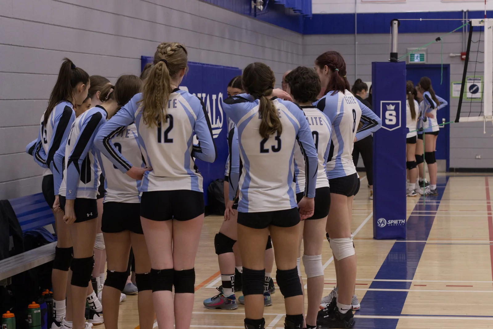 A club volleyball team huddled together courtside before a match